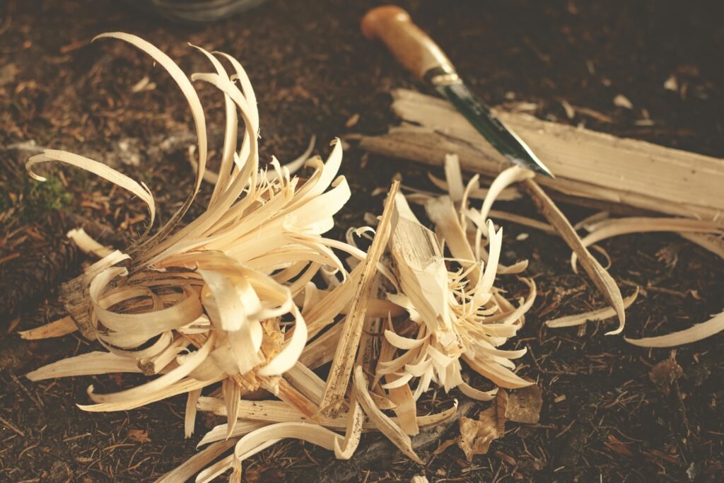 pexels-photo-227577-227577 Woodworking knife and wood shavings on ground, showcasing craftsmanship in a rustic outdoor environment.