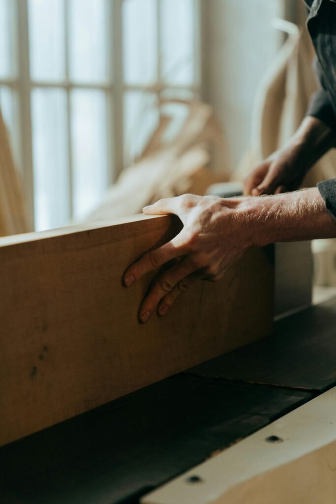 pexels-photo-5089152-5089152 Close-up of a craftsman's hands working with wood in a workshop setting.